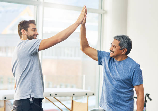 Cropped shot of a young male physiotherapist and his senior patient high fiving after a great session