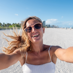 Blonde woman on the beach with sunglasses smiling