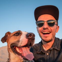 Man smiling with a dog next to him